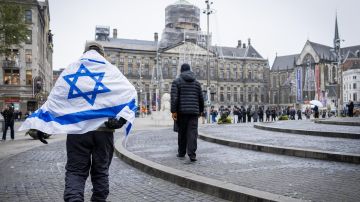 Un hombre sostiene una bandera de Israel en una plaza de Ámsterdam.