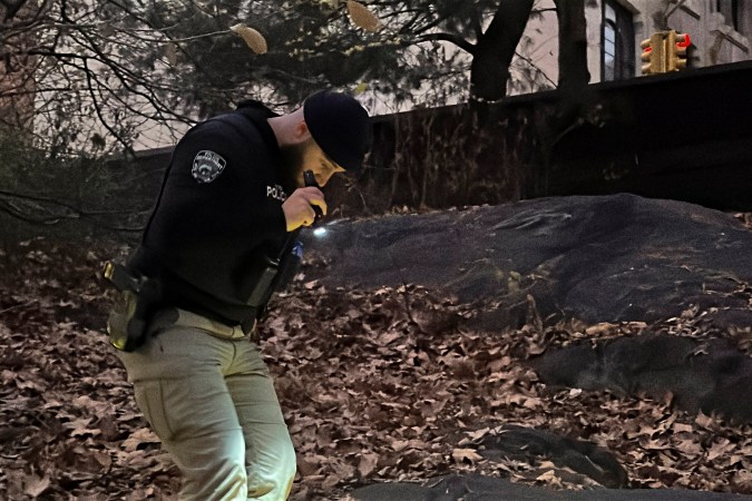 Un agente de policía de la ciudad de Nueva York camina entre la maleza y el follaje en Central Park mientras busca una mochila que, según la policía, dejó caer el sospechoso tras el tiroteo.