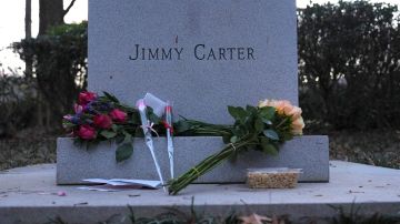 Ramos de flores y cacahuetes se colocan en la base de un busto del expresidente Jimmy Carter en la Biblioteca y Museo Presidencial Jimmy Carter.