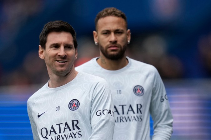 Lionel Messi, del PSG, a la izquierda, sonríe con su compañero de equipo Neymar durante el calentamiento antes del partido de fútbol de la Liga Uno de Francia entre Paris Saint-Germain y Lille en el estadio Parc des Princes, en París, Francia, el domingo 19 de febrero de 2023. (Foto AP/Christophe Ena)