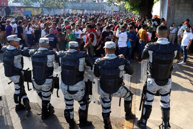 Personal de la Guardia Nacional (GN) bloquea el avance de migrantes a las oficinas de migración este lunes, en el municipio de Tapachula en Chiapas (México).