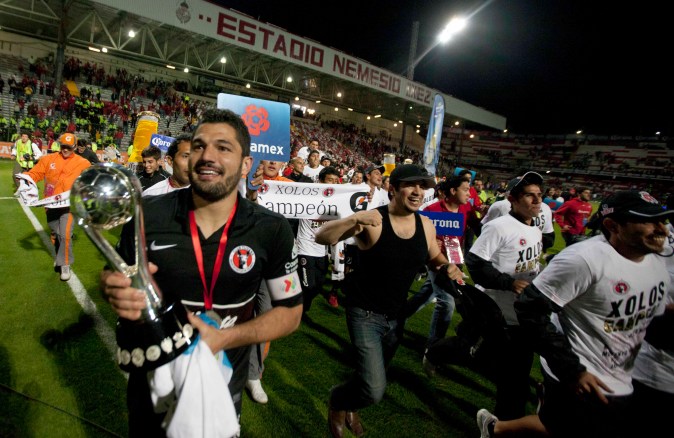 El jugador de Tijuana Javier Gandolfi, a la izquierda, lleva el trofeo de la liga mexicana de fútbol al término de la final de la liga mexicana de fútbol contra Toluca en Toluca, México, el domingo 2 de diciembre de 2012. Tijuana ganó 4-1 en el global. (Foto AP/Eduardo Verdugo)