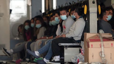 Migrantes con máscaras y grilletes en manos y pies se sientan en un avión militar en Fort Bliss, El Paso, Texas.