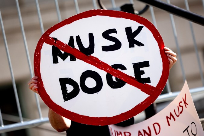 Un manifestante sostiene un cartel que muestra una señal de prohibición de tránsito que dice "Musk DOGE" durante una manifestación para protestar contra las políticas del presidente Trump en el Día de los Presidentes.