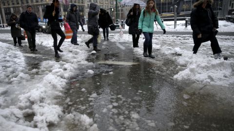 Los peatones se abren paso entre un charco de nieve en el bajo Manhattan.