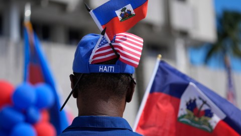 Un hombre lleva banderas estadounidenses y haitianas en su sombrero, mientras miembros de la comunidad haitiana-estadounidense del sur de Florida escuchan a los oradores durante una manifestación para condenar el discurso de odio y la desinformación sobre los inmigrantes haitianos, el domingo 22 de septiembre de 2024, en North Miami, Florida.