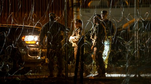 Miembros de la Guardia Nacional del Ejército de Texas conversan mientras patrullan detrás de alambres de púas en las orillas del Río Grande en El Paso, Texas, visto desde Ciudad Juárez, México, el jueves 8 de agosto de 2024 por la noche.