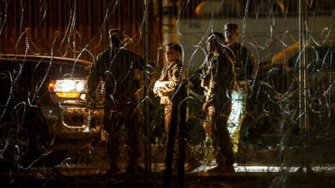 Miembros de la Guardia Nacional del Ejército de Texas conversan mientras patrullan detrás de alambres de púas en las orillas del Río Grande en El Paso, Texas, visto desde Ciudad Juárez, México, el jueves 8 de agosto de 2024 por la noche.