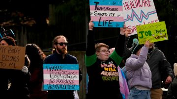 La gente agita carteles durante una protesta a favor de los derechos de las personas transgénero en las afueras del Hospital de Niños de Seattle, luego de que la institución pospusiera algunas cirugías de afirmación de género para menores de edad, luego de una orden ejecutiva del presidente Donald Trump, el domingo 9 de febrero de 2025, en Seattle.