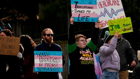 La gente agita carteles durante una protesta a favor de los derechos de las personas transgénero en las afueras del Hospital de Niños de Seattle, luego de que la institución pospusiera algunas cirugías de afirmación de género para menores de edad, luego de una orden ejecutiva del presidente Donald Trump, el domingo 9 de febrero de 2025, en Seattle.