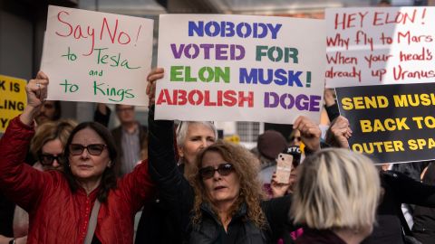 Manifestantes participan en una protesta contra Elon Musk y Tesla afuera de una sala de exposición de Tesla.