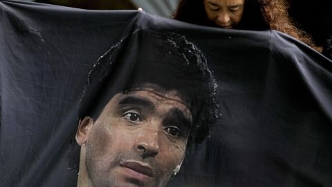 Una fanática de Diego Maradona sostiene una bandera con su imagen.