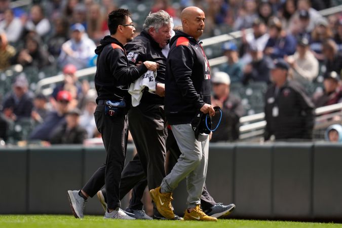 El árbitro de primera base, Hunter Wendelstedt (centro), abandona el campo con el personal médico tras ser golpeado por una bola de foul durante la séptima entrada de un partido de béisbol entre los Mellizos de Minnesota y los Mets de Nueva York, el miércoles 16 de abril de 2025, en Minneapolis. (Foto AP/Abbie Parr)