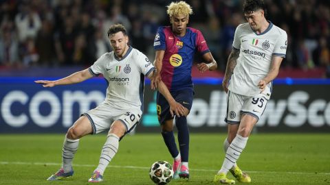 El delantero del FC Barcelona, Lamine Yamal (c), disputa el balón ante los defensores del Inter.