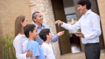 Real estate agent giving keys of their new house to a happy Latin American family