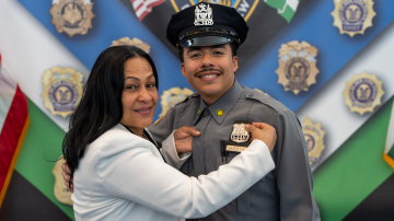 El nuevo oficial es uno de los 30 de origen dominicano que se integran a las filas de NYPD. Aqui en la gráfica acompañado por Leandra Guzmán Feliz, la madre de "Junior".