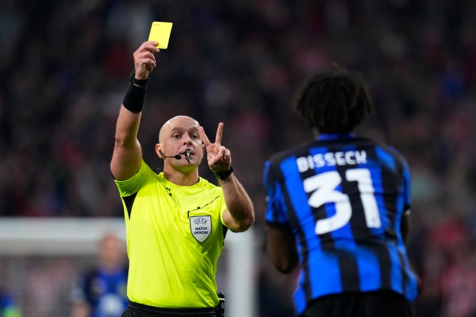 El árbitro Szymon Marciniak muestra una tarjeta amarilla a Yann Aurel Bisseck del Inter de Milán, (Foto AP/Manu Fernandez).