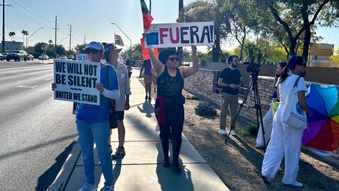 Personas sostienen carteles y banderas durante una manifestación este sábado, en Tucson (Estados Unidos).