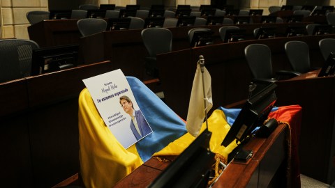 Una imagen del senador colombiano Miguel Uribe Turbay y una bandera colombiana cubren su escaño en el Congreso mientras se encuentra en estado grave.