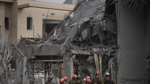 Oficiales del comando del frente interno de Israel inspeccionan el lugar donde un misil lanzado desde Irán impactó en Nes Ziona, Israel.