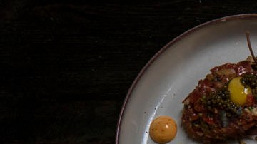 La especialidad de la casa es la parrilla tradicional argentina, con cortes cocinados a fuego abierto y lento, además de ceviches, crudos y mariscos