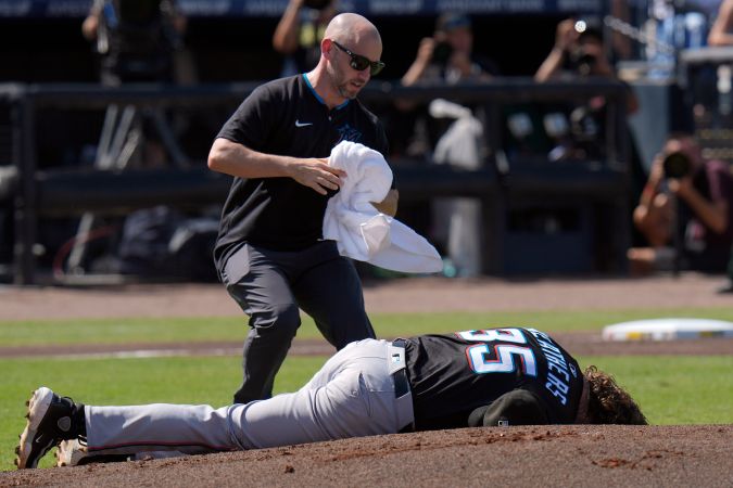 Un entrenador de los Miami Marlins sale corriendo para ayudar al lanzador Ryan Weathers tras recibir un golpe en la cabeza mientras sus compañeros calentaban antes de la primera entrada de un partido de béisbol el sábado 7 de junio de 2025 en Tampa, Florida. (Foto AP/Chris O'Meara)