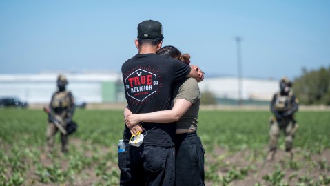 Una pareja se abraza mientras agentes federales de inmigración bloquean el acceso durante una redada en la zona agrícola de Camarillo, California, el jueves 10 de julio de 2025.