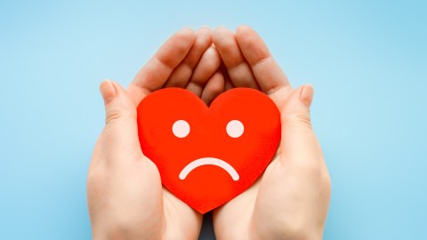 Female,Hands,Hold,A,Paper,Heart,With,A,Sad,Smiley