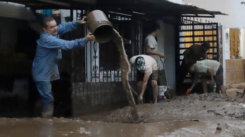 Habitantes de las zonas afectadas por las fuertes lluvias retiran lodo de sus viviendas este domingo, en Huauchinango (México).
