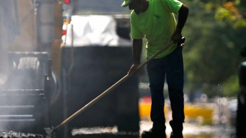 Un trabajador del Departamento de Servicios Generales de Albany extiende asfalto caliente durante un proyecto de pavimentación de calles en Albany, Nueva York.