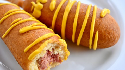 Two,Corn,Dogs,With,Mustard,On,A,White,Plate