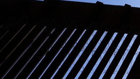 Agentes de la Patrulla Fronteriza y miembros del ejército se encuentran dentro de una puerta en uno de los dos muros fronterizos que separan México de EE.UU.