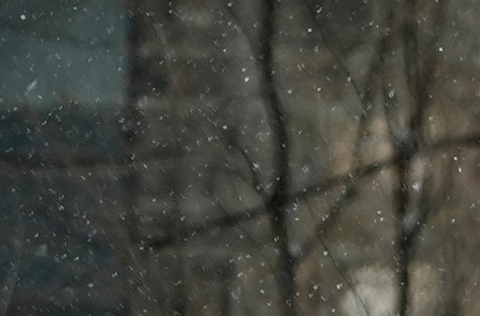 Seorang pengendara mobil membersihkan es dan salju dari kaca depan kendaraan saat badai musim dingin.