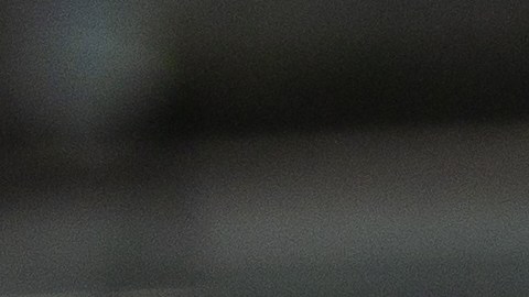 A young adult Hispanic female stands with arms crossed, smiling at the camera, dressed in casual attire within a vibrant coworking office environment.