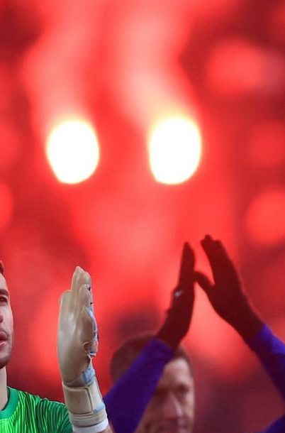 Los jugadores del Barcelona saludan a sus aficionados, mientras se ven bengalas encendidas por los seguidores del Slavia Praga tras finalizar el partido.