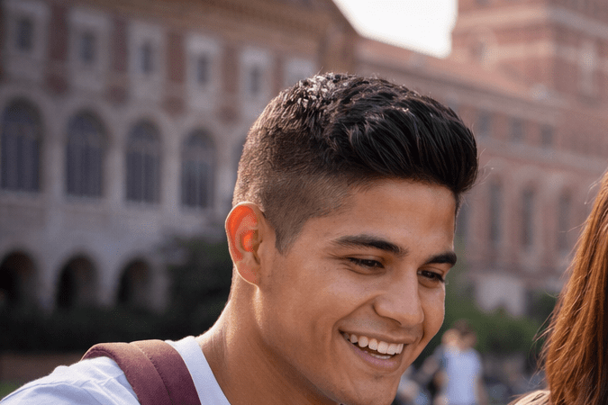 Estudiantes latinos trabajando en grupo con laptop y libros en campus universitario de Estados Unidos
