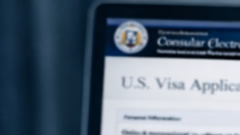 Persona revisando redes sociales mientras completa formulario de visa de Estados Unidos en computadora