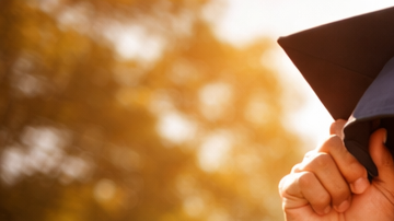Joven atleta latino celebrando graduación universitaria en campus de Estados Unidos con uniforme deportivo y diploma