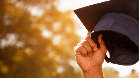 Joven atleta latino celebrando graduación universitaria en campus de Estados Unidos con uniforme deportivo y diploma