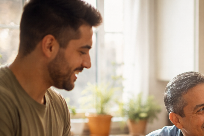 Familia latina con hijos adultos comparte un momento cotidiano en la cocina de su casa.