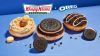 Primer plano de la nueva colección de donas Krispy Kreme x Oreo, mostrando la dona Golden Oreo con chispas de colores, la Chocolate Oreo Dream con glaseado oscuro y la clásica Cookies & Kreme sobre un fondo de marca.