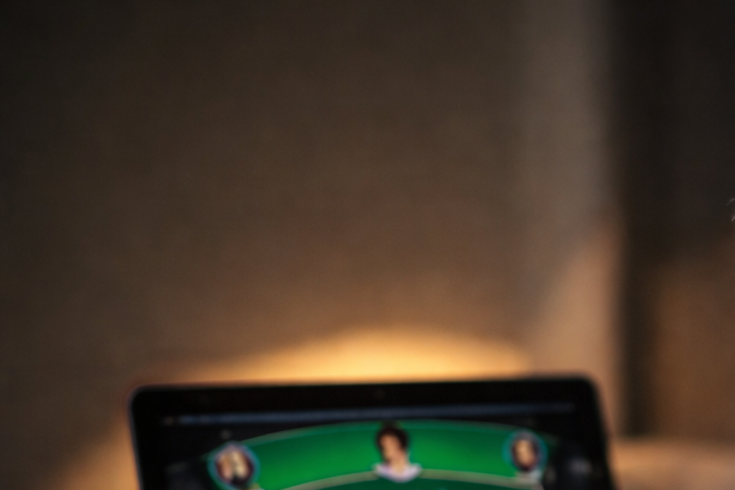 Hombre con gesto de angustia frente a una laptop con póker en línea y fichas de casino sobre la mesa