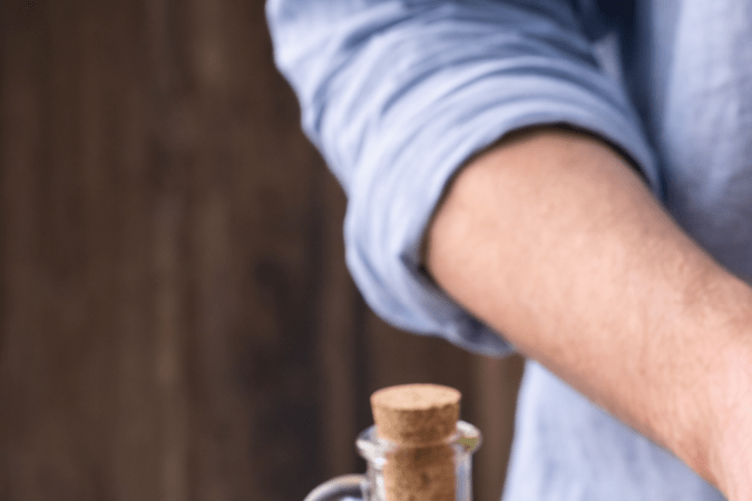 Manos preparando mayonesa con ajo en licuadora con huevo, aceite, limón y ajo sobre mesa de cocina