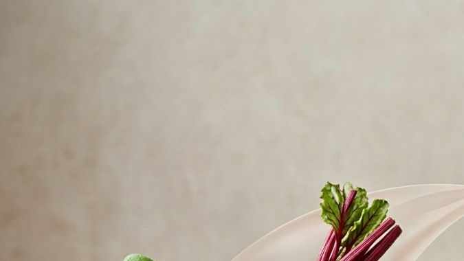 Composición de alimentos altos en oxalatos como espinacas, remolacha y chocolate junto a una ilustración anatómica de un riñón con cálculos renales.