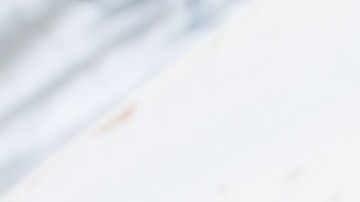 Un primer plano de un tazón de queso cottage artesanal en un fondo blanco. El queso tiene una textura granulada y se ve apetitoso.