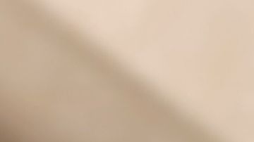 Primer plano de un vaso de Chai Latte de Starbucks con leche vaporizada y espuma, mostrando la textura cremosa de la bebida de té negro y especias sobre una mesa de madera