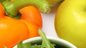 Imagen de dos figuras ilustrativas de los riñones rodeada de alimentos saludables,