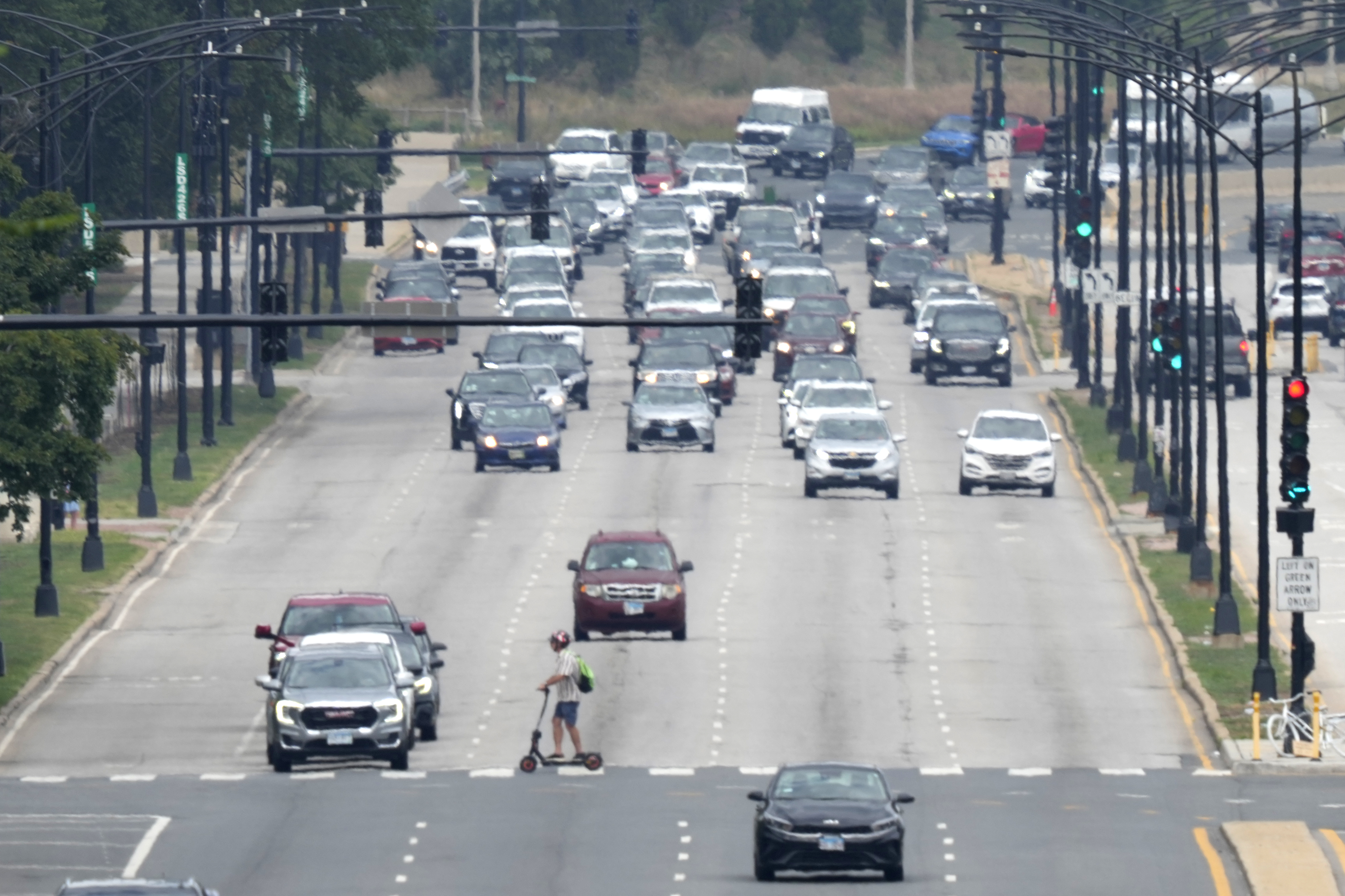 Un peatón cruza DuSable Lake Shore Drive en patinete eléctrico