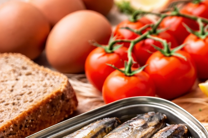 Plato con un pequeño pescado azul acompañado de alimentos saludables como limón, tomate y aceite de oliva, considerado por nutricionistas uno de los alimentos más completos