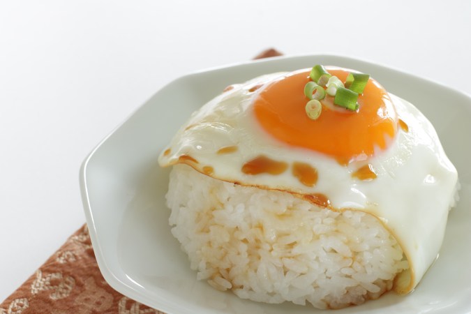 Arroz con huevo sobre un plato blanco y fondo neutro.